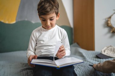 Kafkasyalı bir çocuk. Altı yaşında bir çocuk evde kitap okuyor.