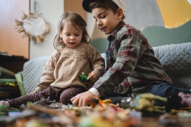 Small caucasian boy and girl siblings brother and sister children play at home sit on the floor at home childhood development growing up concept copy space domestic life
