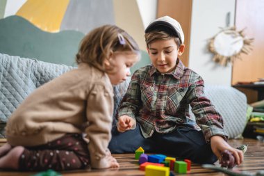Small caucasian boy and girl siblings brother and sister children play at home sit on the floor at home childhood development growing up concept copy space domestic life