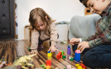 Small caucasian boy and girl siblings brother and sister children play at home sit on the floor at home childhood development growing up concept copy space domestic life