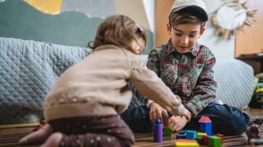Small caucasian boy and girl siblings brother and sister children play at home sit on the floor at home childhood development growing up concept copy space domestic life