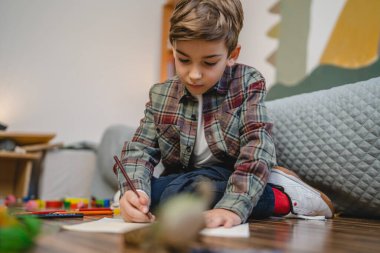 one small caucasian boy Gradeschooler child draw with crayon at home