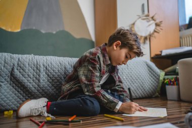 one small caucasian boy Gradeschooler child draw with crayon at home