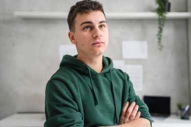 one man teenager stand in room at home wear green hoodie waist up