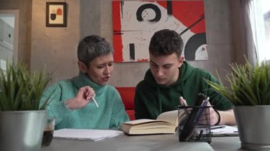 One student teenage caucasian man study learn with help of his tutor professor or mother senior woman at home having private lesson to prepare for exam education concept real people