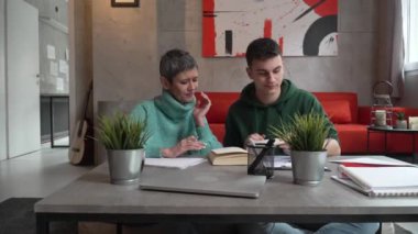 One student teenage caucasian man study learn with help of his tutor professor or mother senior woman at home having private lesson to prepare for exam education concept real people