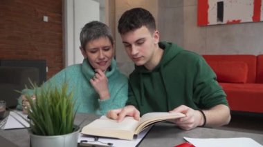 One student teenage caucasian man study learn with help of his tutor professor or mother senior woman at home having private lesson to prepare for exam education concept real people