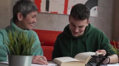 One student teenage caucasian man study learn with help of his tutor professor or mother senior woman at home having private lesson to prepare for exam education concept real people