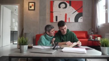 One student teenage caucasian man study learn with help of his tutor professor or mother senior woman at home having private lesson to prepare for exam education concept real people