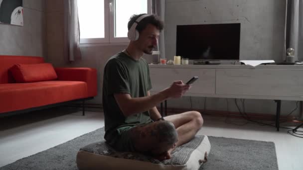 Yetişkin Bir Beyaz Erkek Evde Oturup Kulaklık Akıllı Telefon Kullanarak — Stok video