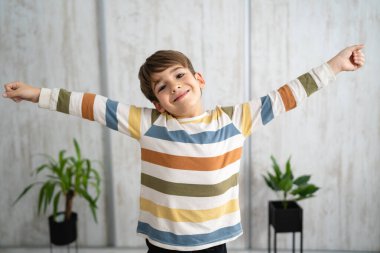 portrait of caucasian boy six years old raise and spread arms at home