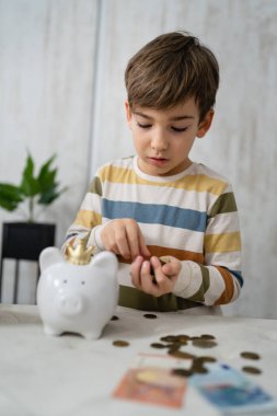 portrait of caucasian boy six years old saving money with piggy bank