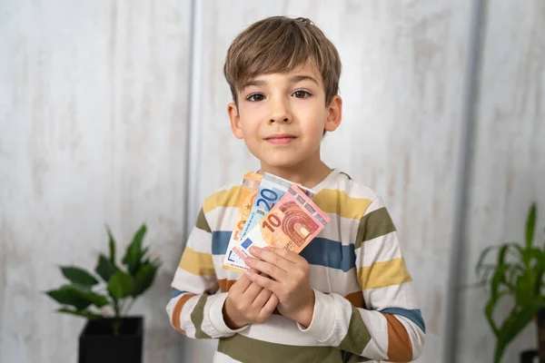 portrait of caucasian boy six years old hold euro banknotes saving