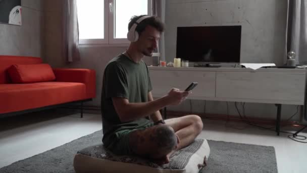 Ένας Ενήλικας Καυκάσιος Άνδρας Κάθεται Στο Σπίτι Ακουστικά Στο Κεφάλι — Αρχείο Βίντεο