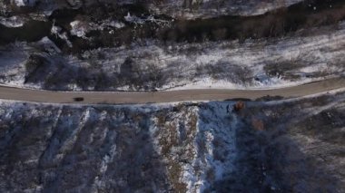 Car drive in snow winter day on the road in mountain range aerial view