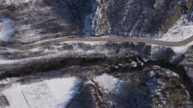 Car drive in snow winter day on the road in mountain range aerial view