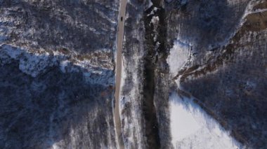 Car drive in snow winter day on the road in mountain range aerial view