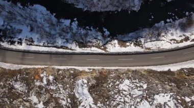 Car drive in snow winter day on the road in mountain range aerial view