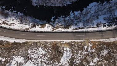 Car drive in snow winter day on the road in mountain range aerial view