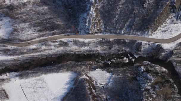 山岳地帯の道路上の雪の冬の日の車のドライブ航空ビュー — ストック動画