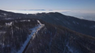 Car drive in snow winter day on the road in mountain range aerial drone view old mountain stara planina babin zub 