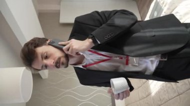 one man adult caucasian businessman wear suit in hotel room while taking a brake or prepare for work hold cup of coffee and smartphone making a phone call talk real people