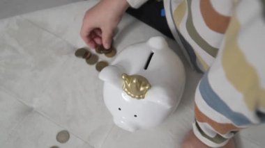 close up on hands of unknown children putting money coins in the piggy bank finance and saving investment concept