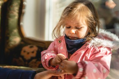 small Caucasian girl toddler eat chocolate bar waits up portrait
