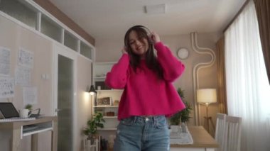 One woman young caucasian female teenager dancing alone at home with headphones on her head having fun while listen to the music happy smile real people copy space