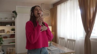 One woman young caucasian female teenager dancing alone at home with headphones on her head having fun while listen to the music happy smile real people copy space