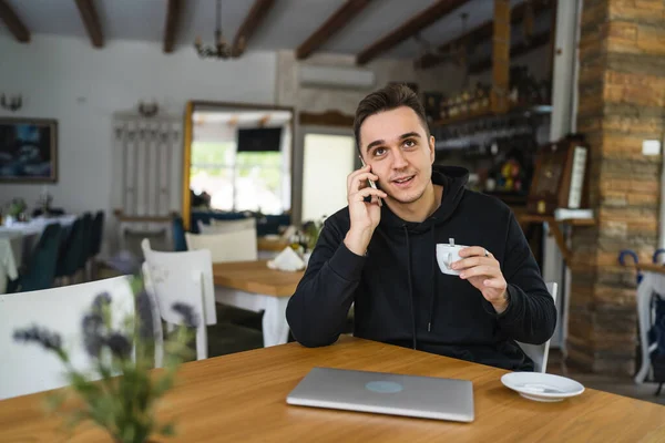 One man sitting at the table at cafe or restaurant wear casual using mobile phone to make a call talking communication while hold a cup of coffee real people copy space