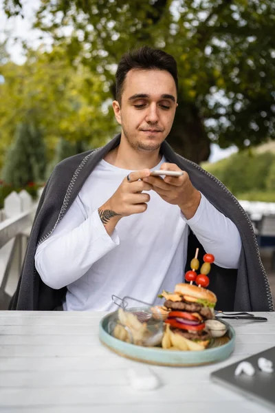 Ένας Άνδρας Καυκάσιος Άνδρας Κάθεται Στη Βεράντα Του Εστιατορίου Χρησιμοποιώντας — Φωτογραφία Αρχείου
