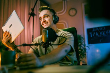 One man caucasian male blogger or vlogger gesticulating while streaming video podcast in broadcasting studio use microphone and headphones famous influencer shooting video for channel podcast