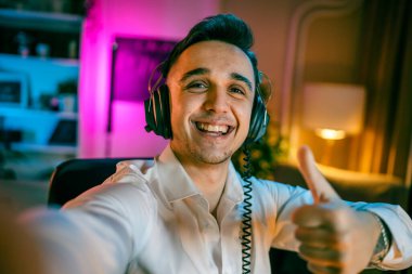 Self portrait of one man caucasian male streamer blogger or content creator with headphones on his head happy smile confident in his studio copy space user generated content UGC