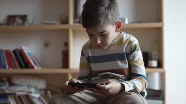 Egy Fiú Kaukázusi Gyermek Óvodás Tartsa Okostelefon Mobiltelefon Otthon Játszani — Stock videók