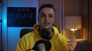 One man caucasian male blogger or vlogger gesticulating while streaming video podcast in broadcasting studio use microphone and headphones famous influencer shooting video for channel podcast