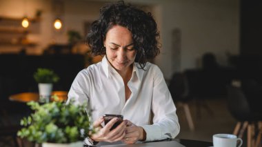 İş yerindeki kadın yönetici ya da girişimci cep telefonu akıllı telefonu kullanır iş kadını iletişim konseptinden fren alırken beyaz gömlek giyer gerçek kişi kopyalama alanı SMS mesajları gönderir