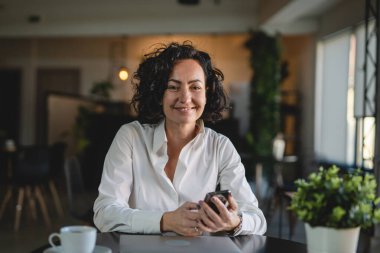 İş yerindeki kadın yönetici ya da girişimci cep telefonu akıllı telefonu kullanır iş kadını iletişim konseptinden fren alırken beyaz gömlek giyer gerçek kişi kopyalama alanı SMS mesajları gönderir