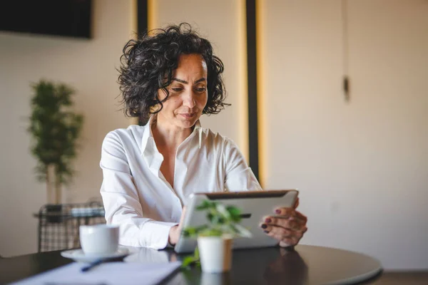 ある女性実業家はカフェやレストランのマネージャーでテーブルに座って仕事でデジタルタブレットを使用成熟した女性起業家ビジネスをオンラインで行う実際の人々はスペースをコピー — ストック写真
