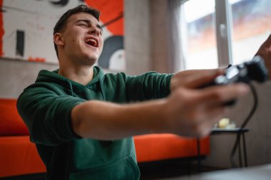 Beyaz tenli bir genç erkek, evinde video oyunu oynuyor ve kaybediyor.