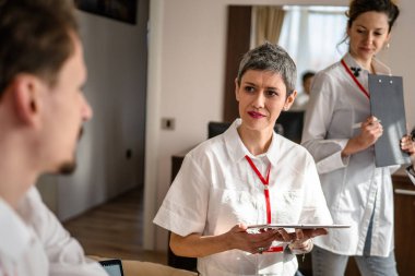 Kafkas kadın ve erkek grupları, satış sunumuna hazırlanırken otel odasında erkek ve kadın işadamı ve kadın yönetici ya da satıcı konferansına hazırlanıyorlar.