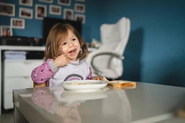 ある女の子は白人の幼児女性の子供が家のテーブルで食べます — ストック写真