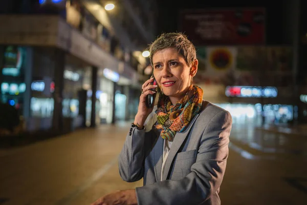 一人のシニア女性短い白髪の白人女性は話すか 夜に街で呼び出しを行うために携帯電話を使用します幸せな笑顔自信を持ってリアルな人コピースペース — ストック写真