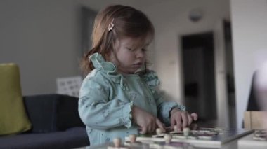 Bir beyaz çocuk, iki yaşında evde tek başına oyun oynuyor. Çocukluk gelişimi kavramının içine tahta parçaları koyuyor.