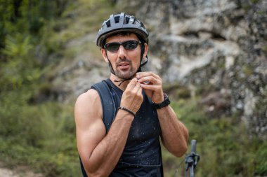 One adult caucasian man ride electric e-bike bicycle in sunny summer day getting ready in front of the house wear protective helmet and eyeglasses real people copy space