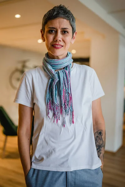 一位高年级 头戴短发的高加索女人独自站在咖啡店或餐馆里 手上戴着白衬衫纹身 自信而快乐地微笑着真实的人复制空间 — 图库照片