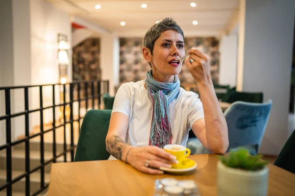 一人の女性シニア白人女性はカフェやレストランで座っているコーヒーのカップを持っています本物の人々は一人で座っている現代の灰色の短い髪の人のコピースペース — ストック写真