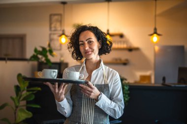 Kafe ya da lokantada çalışan olgun bir kadın garson kahve tepsisi taşıyor. İş yerindeki bayan girişimci. Gerçek insanlar uzay küçük işletme konseptini kopyalıyor.