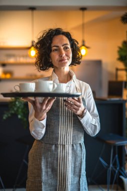 Kafe ya da lokantada çalışan olgun bir kadın garson kahve tepsisi taşıyor. İş yerindeki bayan girişimci. Gerçek insanlar uzay küçük işletme konseptini kopyalıyor.