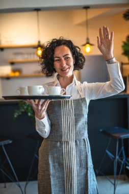 Kafe ya da lokantada çalışan olgun bir kadın garson kahve tepsisi taşıyor. İş yerindeki bayan girişimci. Gerçek insanlar uzay küçük işletme konseptini kopyalıyor.